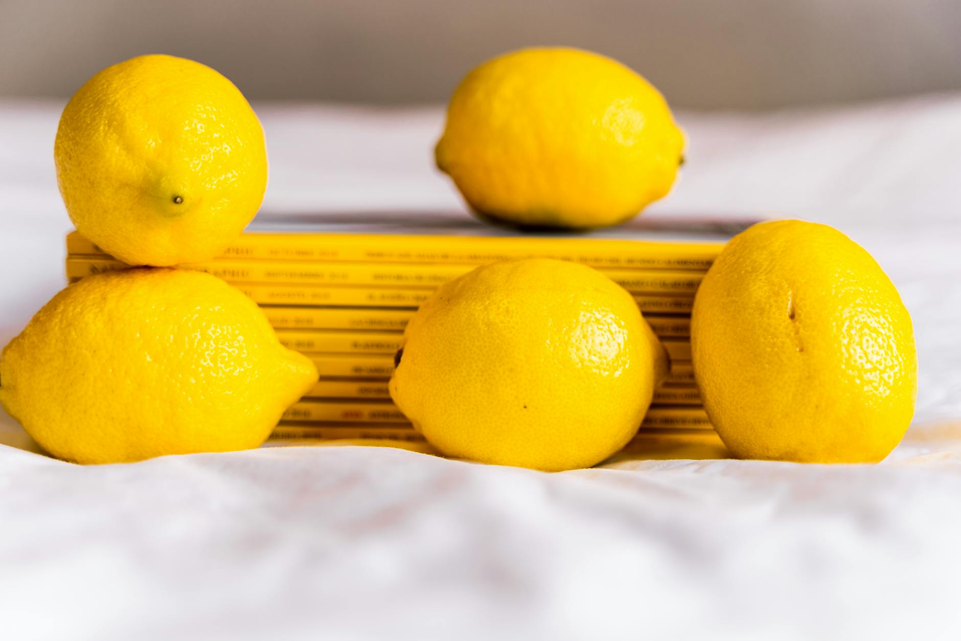 Fresh lemons on a white plate with vibrant yellow background, symbolizing renewal and freshness